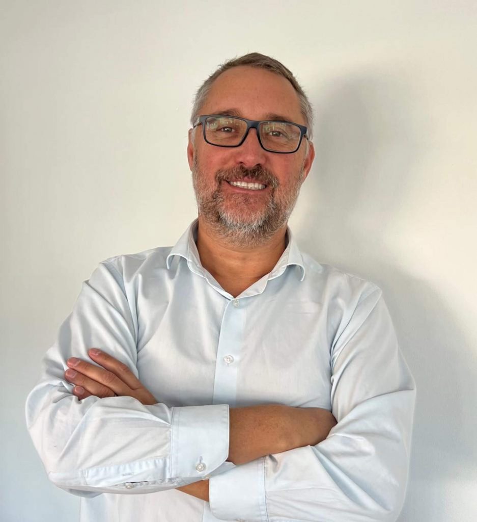 Juan Pablo Andreani, socio del Comité de Packaging de Asimpres y gerente general de Selecta Envases. Hombre de mediana edad con camisa blanca y lentes con marco negro, cruza los brazos posando y sonriendo para la foto .